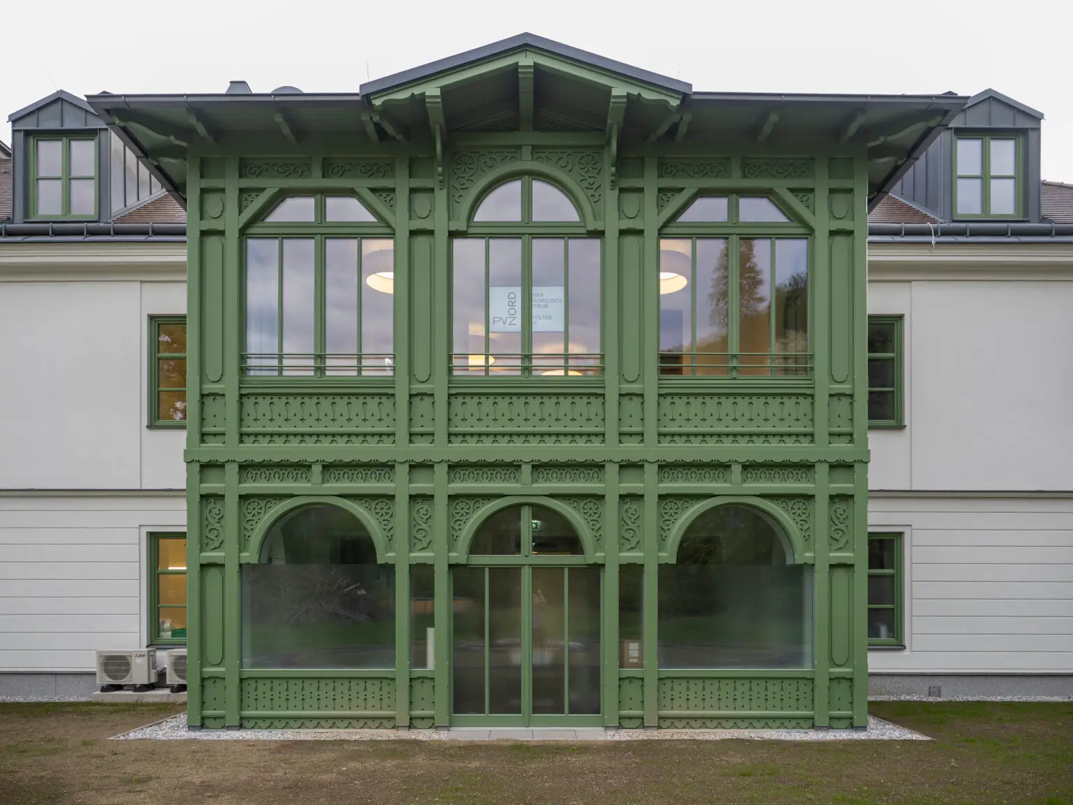Detailaufnahme der reich verzierten, grün gestrichenen Veranda mit Rundbögen und Schnitzwerk