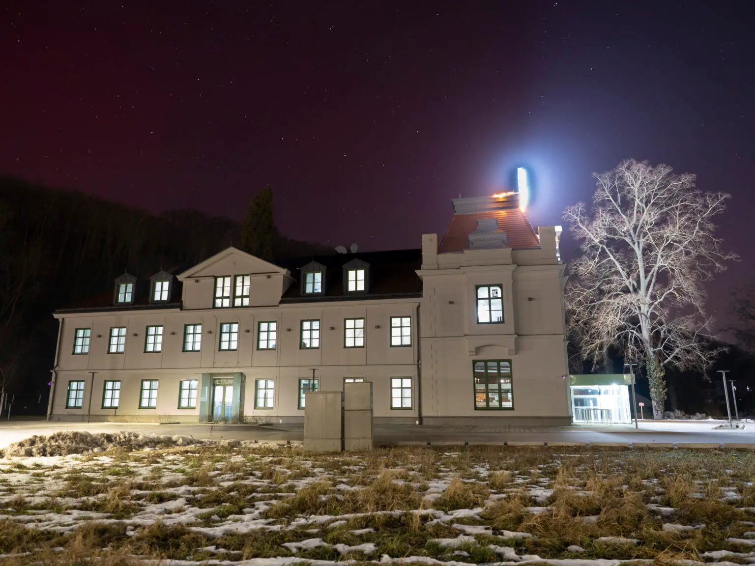 Winterliche Nachtaufnahme der beleuchteten Fassade unter dem Sternenhimmel